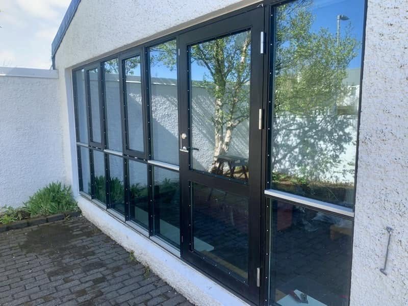 Gluggar og glerhurð með dökkum römmum.