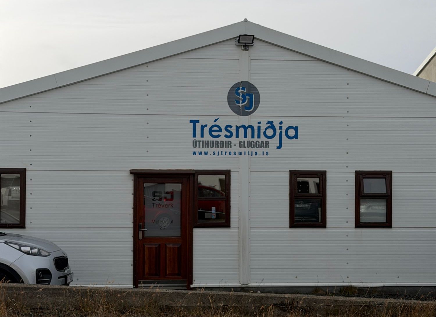 Verkstæði SJ Tréverks á Melabraut 20. Á hvítri framhliðinni stendur Trésmiðja, útihurðir og gluggar.